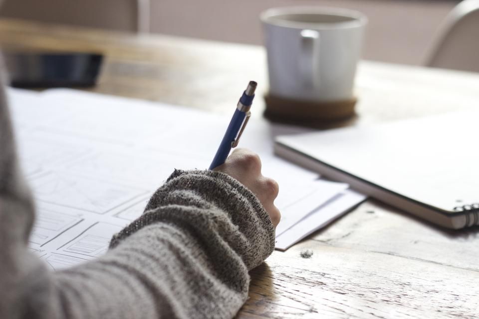 An open notebook and a cup of coffee on a wooden table.