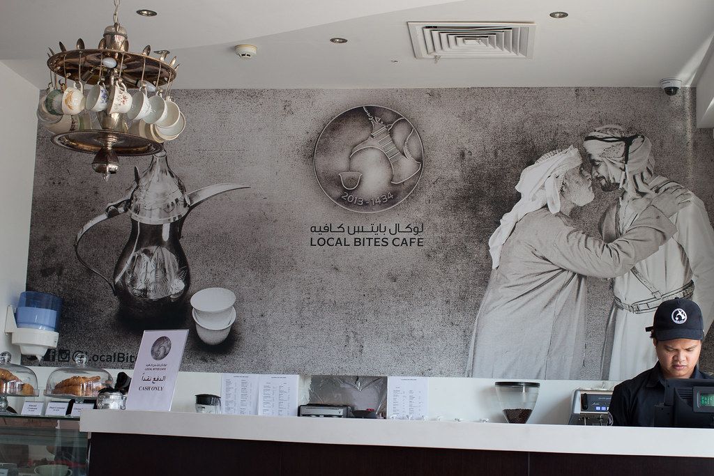 Coffee cups and cakes displayed on a cafe counter.