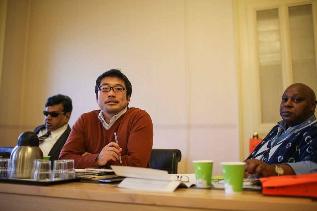 Two people discussing papers across a small meeting table.