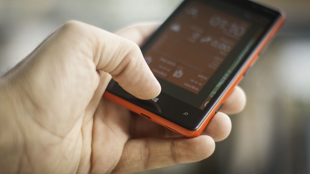 A person holding a smartphone beside an open notebook.