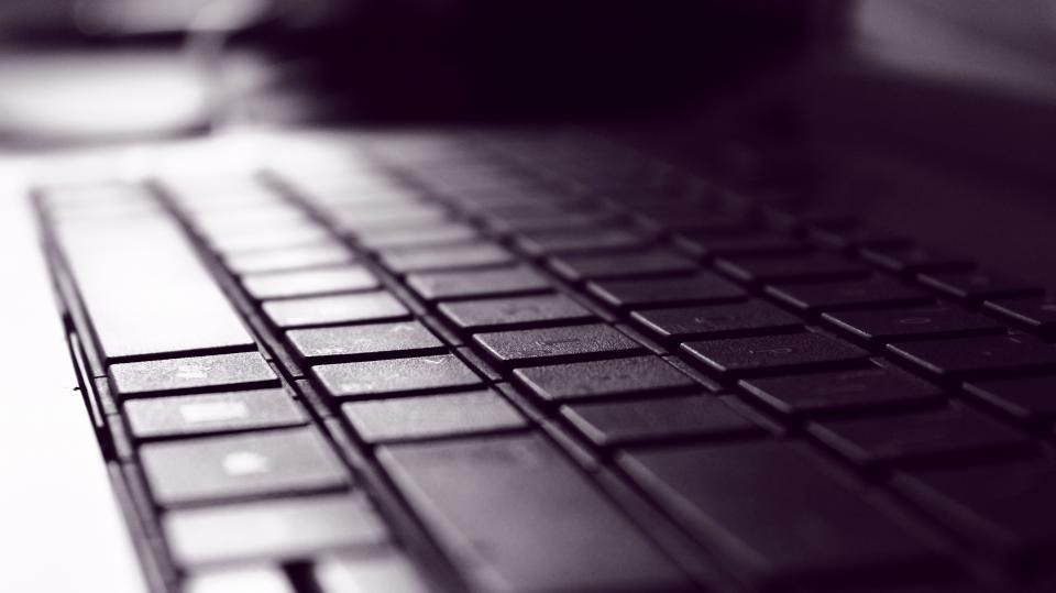 Hands using a laptop keyboard beside a mouse.