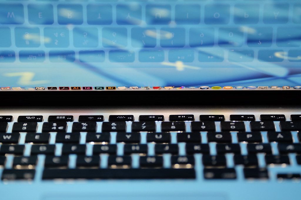 A person using a laptop keyboard at a wooden desk.