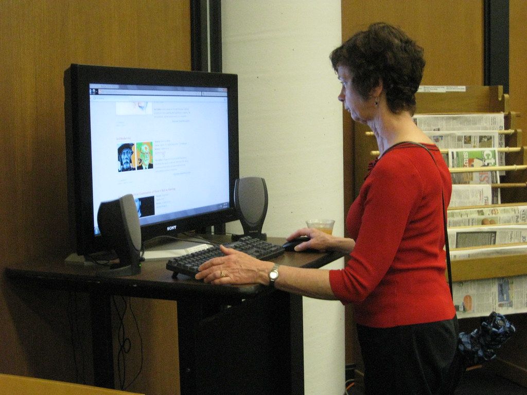 A salon owner standing at a reception counter beside appointment cards.