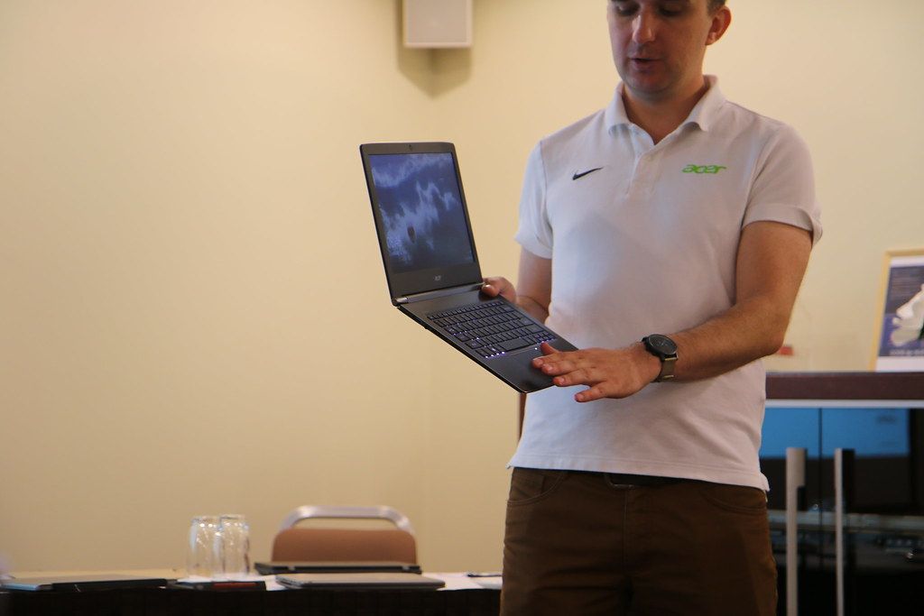 A person marking a checklist in a notebook beside an open laptop.