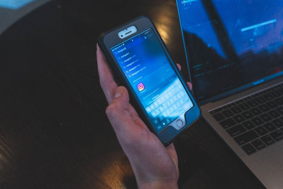 A person holding a smartphone in both hands above a table.